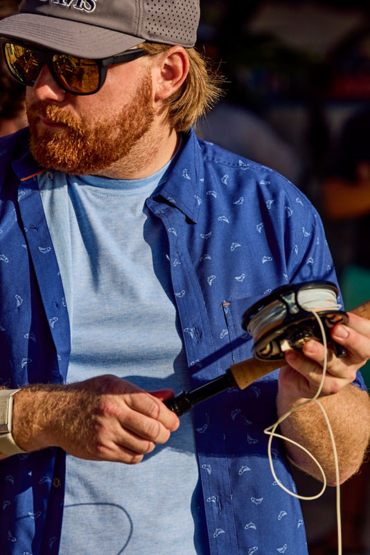 An angler winds fly line onto a reel.