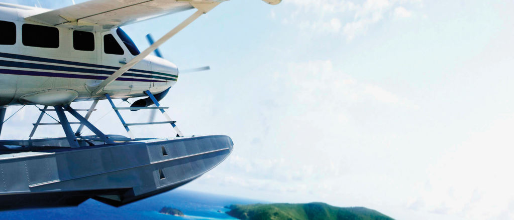 Float plane flying over water with islands