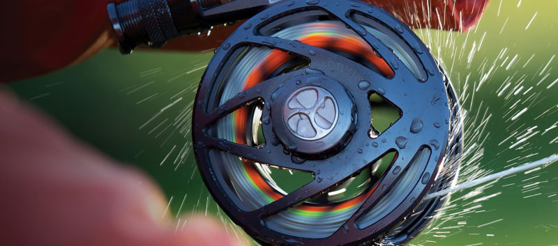 A close shot of a Mirage fly reel spinning with water flying in all directions.