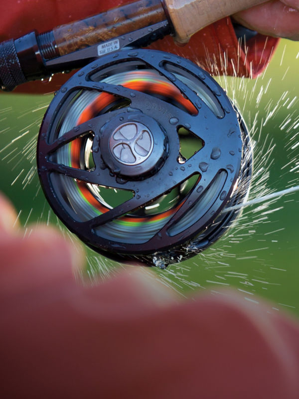 A close shot of a Mirage fly reel spinning with water flying in all directions.