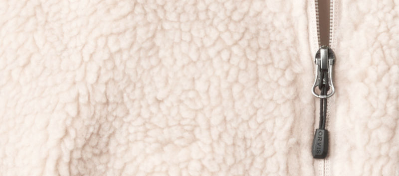A closeup of the material from a cream fleece pullover and zipper.