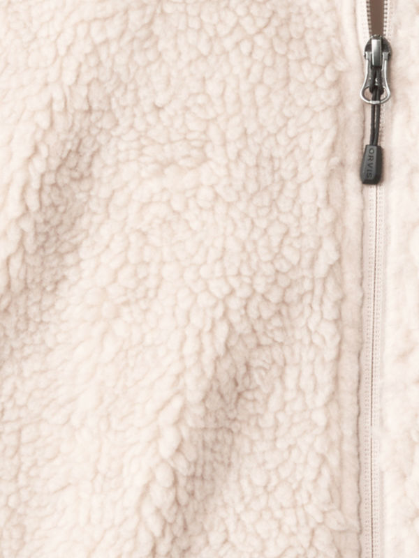 A closeup of the material from a cream fleece pullover and zipper.