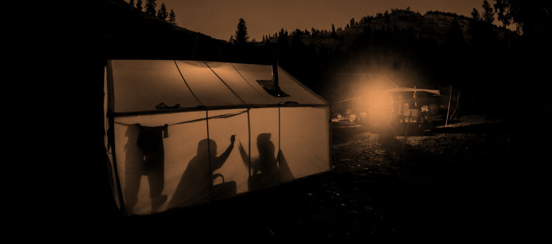 A campsite including two people high-fiving in a tent.