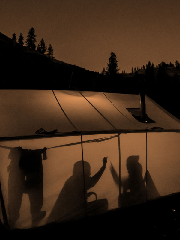 A campsite including two people high-fiving in a tent.