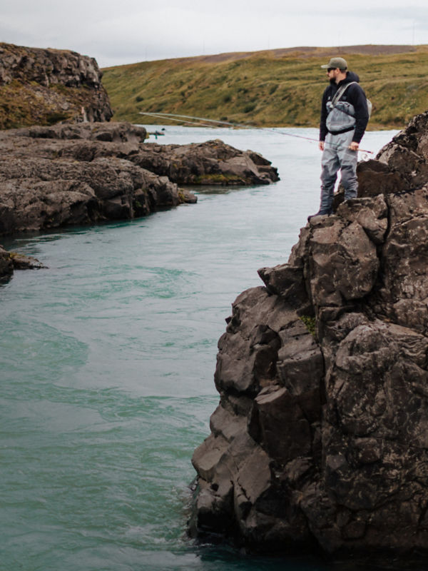Three people fishing off a boat during sunset.