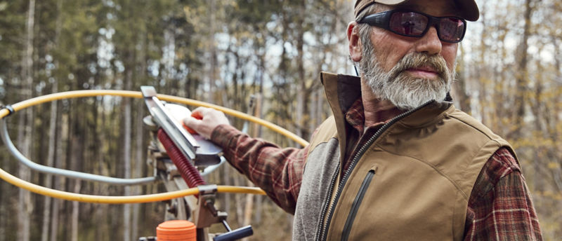A man stands by a clays launcher looking over his shoulder.