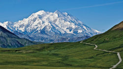 Alaskan mountain towering over green meadow