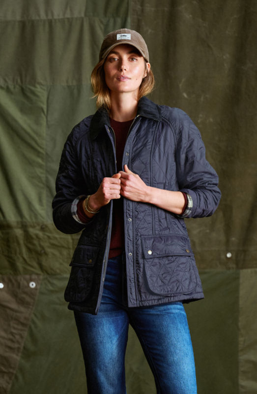 A woman wearing a navy quilted  jacket with a brown ball cap.