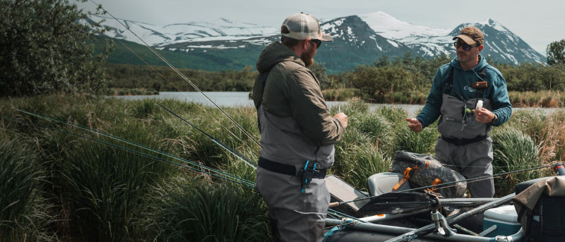 Two men preparing for a fishing adventure next to a loaded raft.