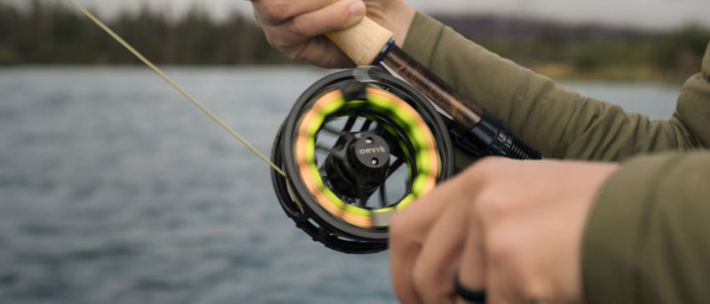 Two hands work a fly rod with the Hydros reel spinning.