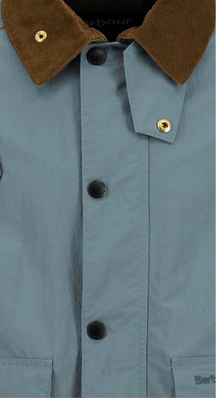 A closeup of the brown corduroy collar of a blue Barbour jacket.