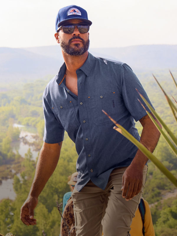 A man hiking up a mountain with the valley laid out behind him.