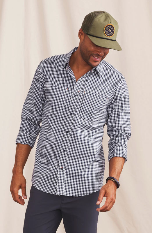 A model is wearing a dark blue gingham button-down shirt with an olive ball cap.
