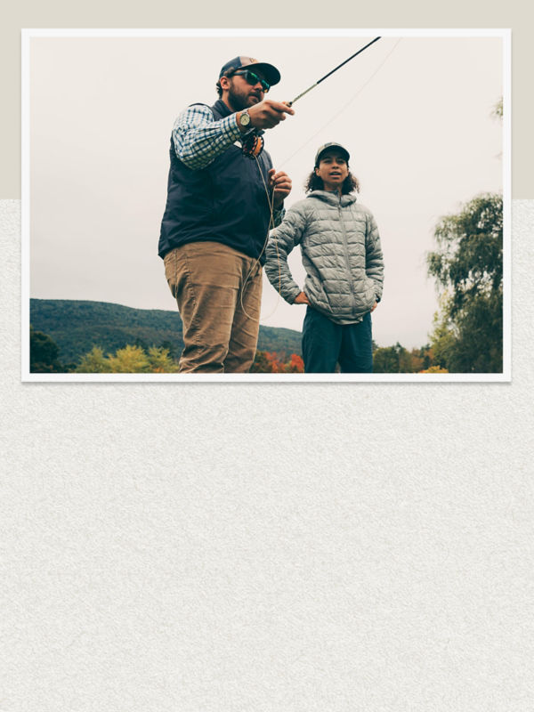 An instructor demonstrates a fly cast for a student.