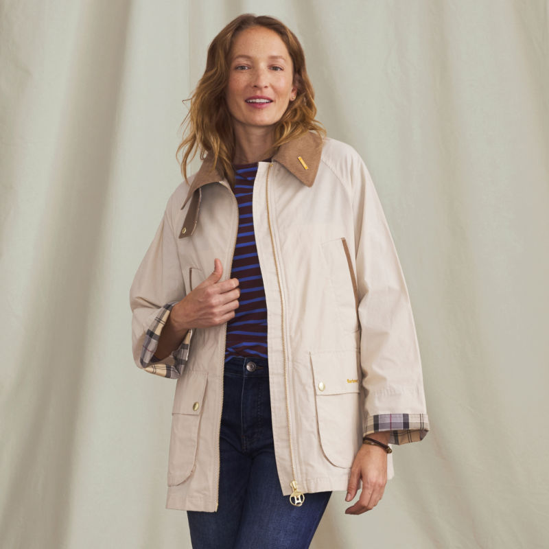 A model wearing a cream Barbour&reg; rain jacket with plaid lining.