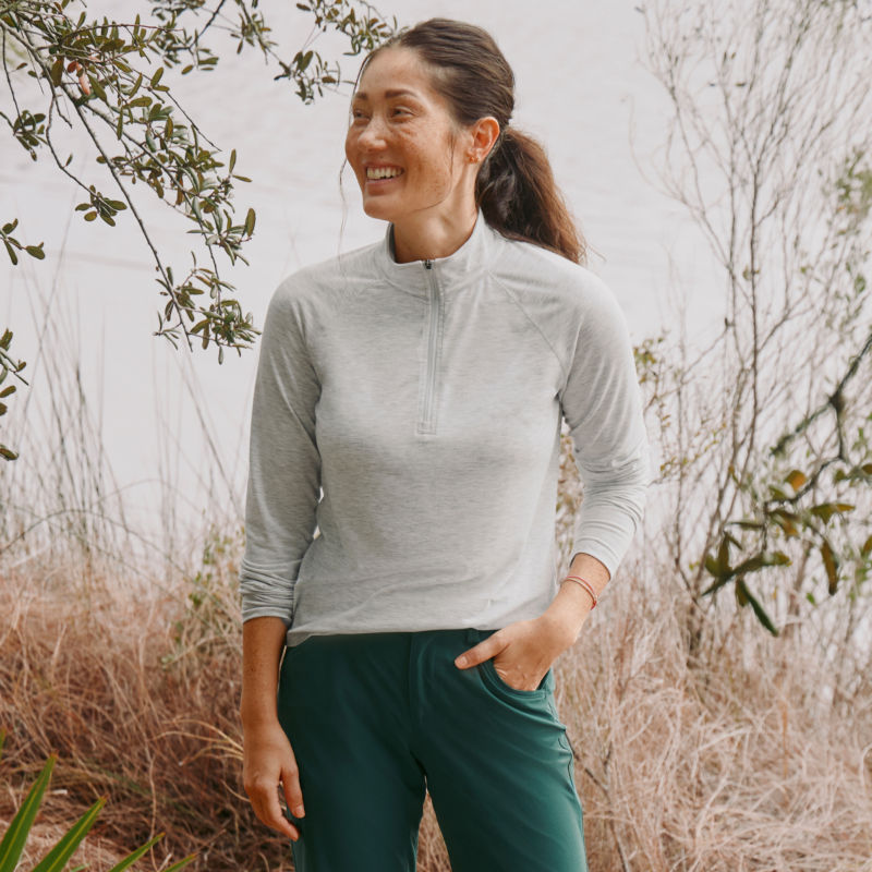 A woman stands outside on a foggy morning wearing a sun protective quarter zip.
