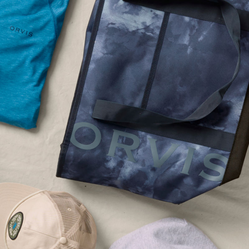 Several gifts laid on a cream background including a tote bag and ball cap.