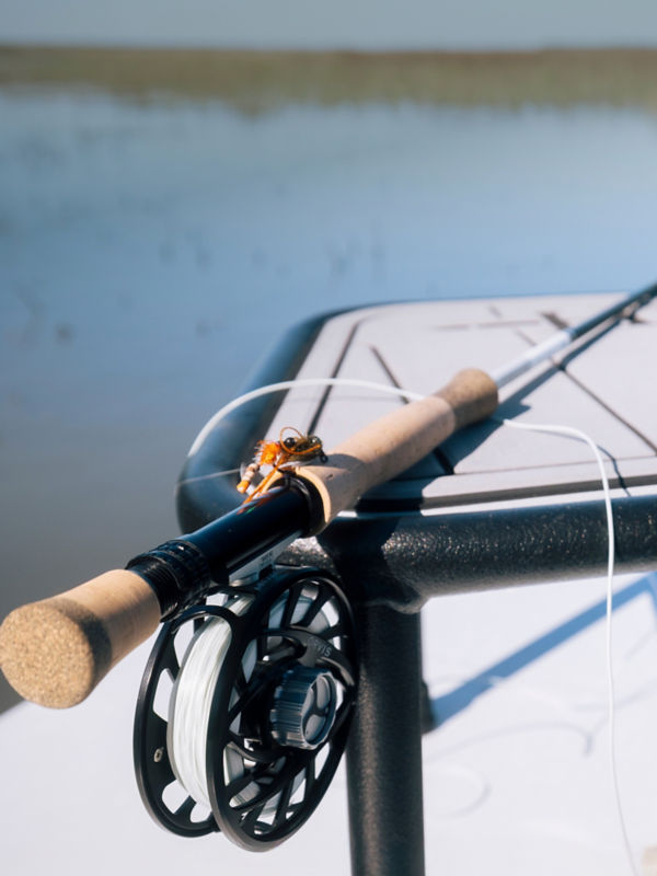 A close view of the butt of a fly rod with reel laid on a boat.