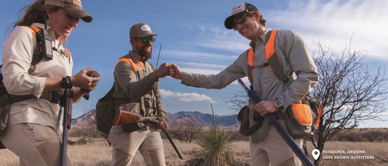 Three hunters in the field celebrating with a fist bump.