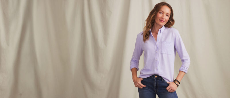 A model wearing lavender button-down shirt over blue jeans.