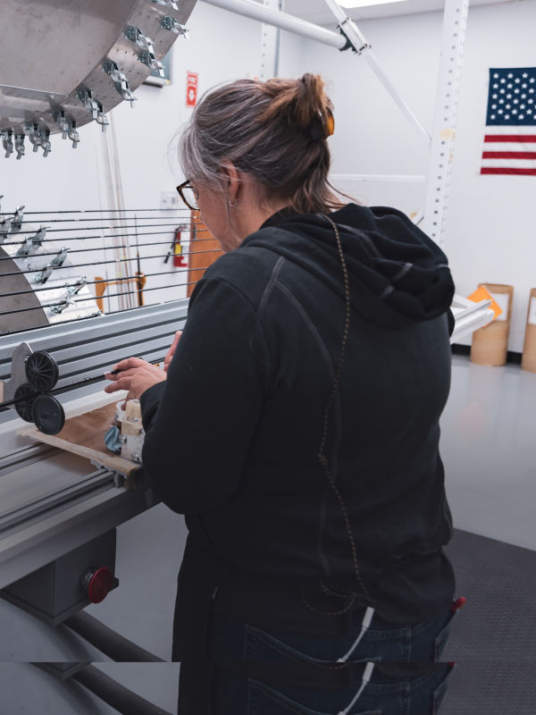 An Orvis rod shop employee working on a fly rod on complex machinery.