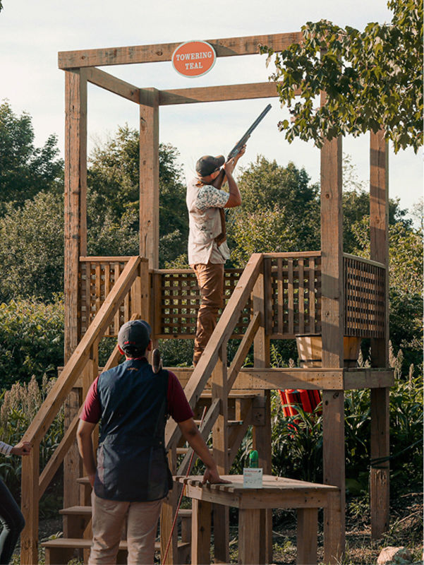 A person stands on a shooting platform shooting clays at Orvis Sandanona.