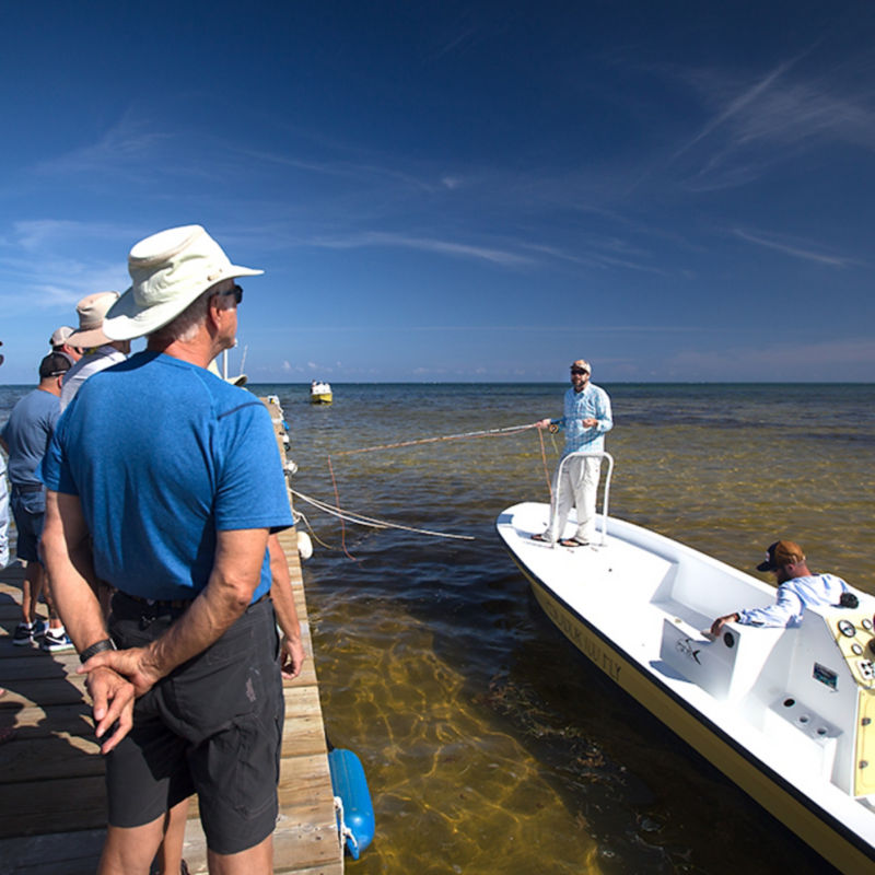 Students watch a fishing guide demonstrate casting from a boat in Belize.