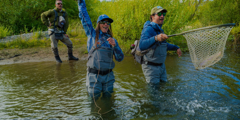 An angler celebrates hooking a fish with two other anglers watching.