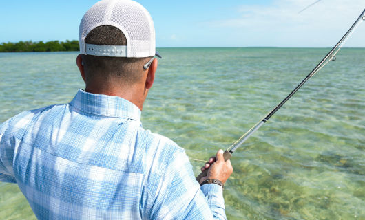 An image from the back of an angler pulling his line taught in tropical waters.