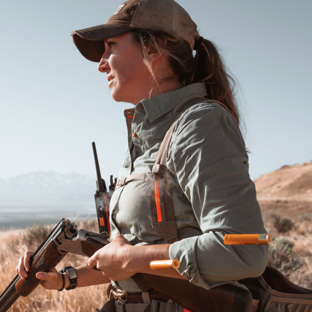 A hunter breaks her shotgun down to move safely.
