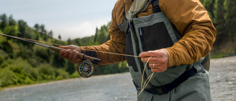Tom Rosenbauer fly fishing in a scenic river landscape.