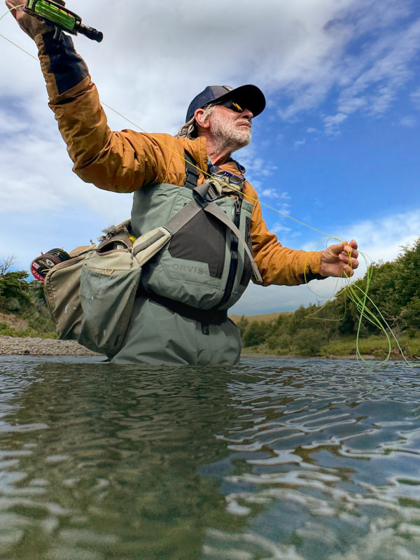 Tom Rosenbauer fly fishing in a scenic river landscape.