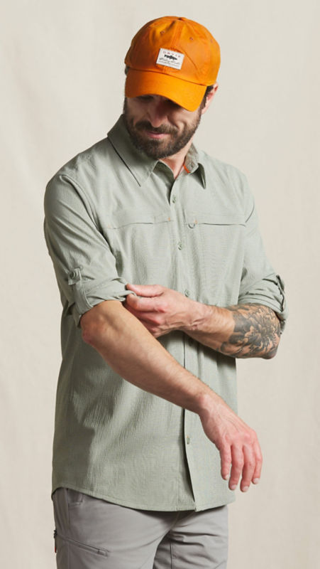 A man adjusts the rolled up sleeves of his button-down shirt.