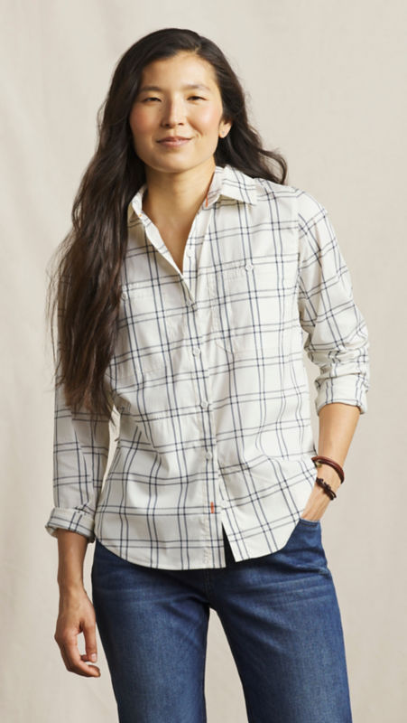 A model wearing plaid button-down shirt with her hand in her front jean pocket.
