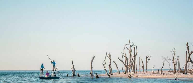 Three people in a boat flats fishing on the Florida coast.