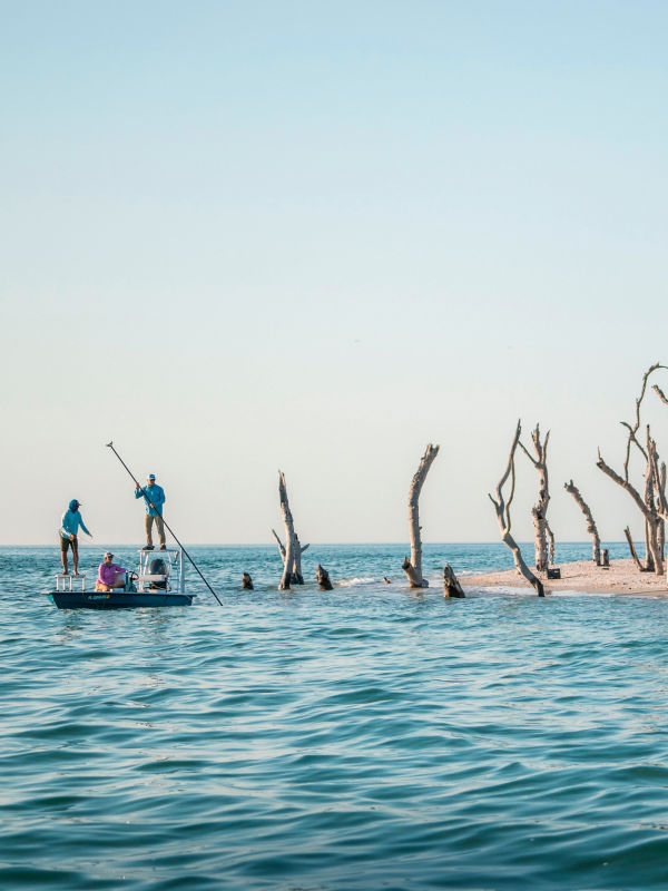 Three people in a boat flats fishing on the Florida coast.