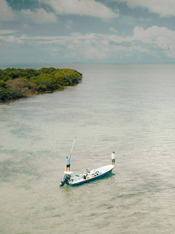 Three people fly fishing from a boat in El Pescador, Belize.