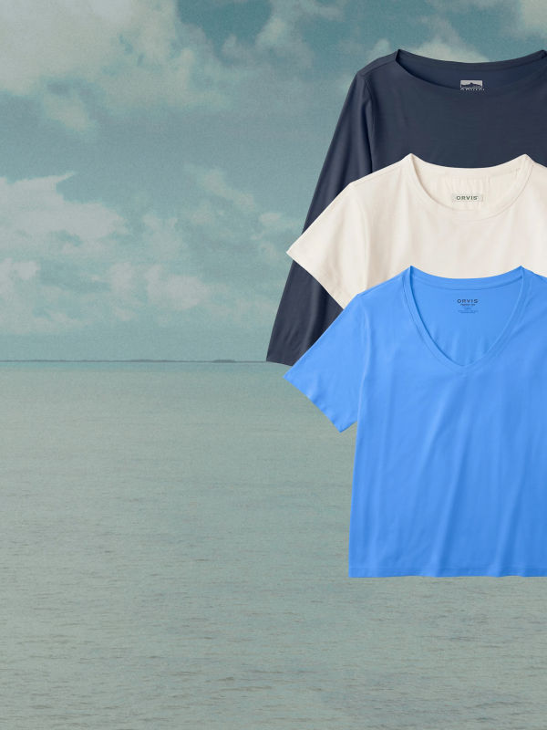 Three women's t shirts superimposed over a background of ocean and sky.