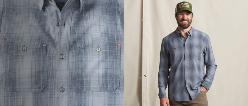 A model wearing a plaid long-sleeve button-up shirt, brown pants, and green baseball cap. 