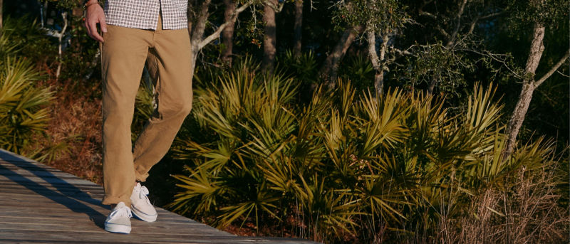 A waist-down image of a man walking along a dock.