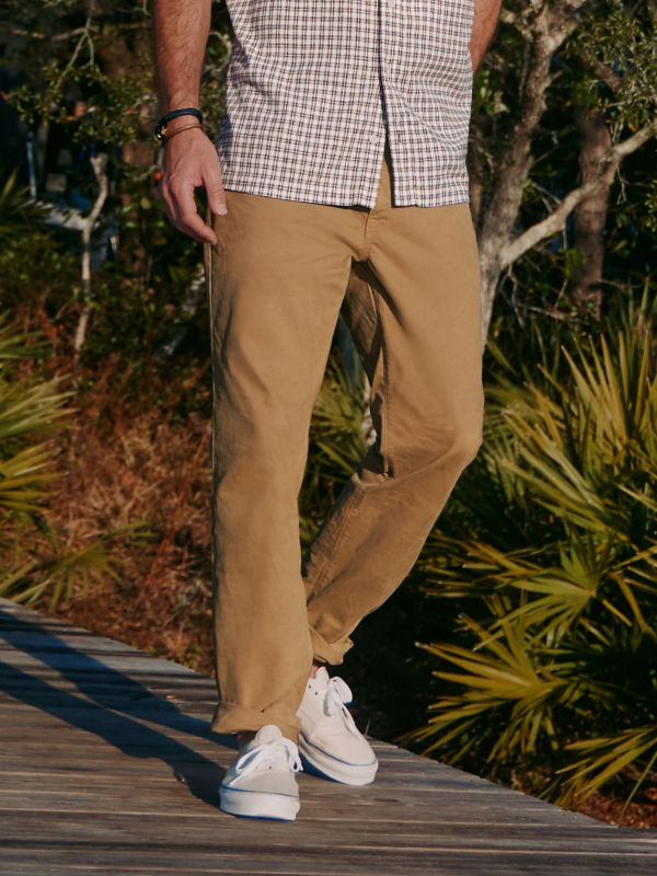 A waist-down image of a man walking along a dock.