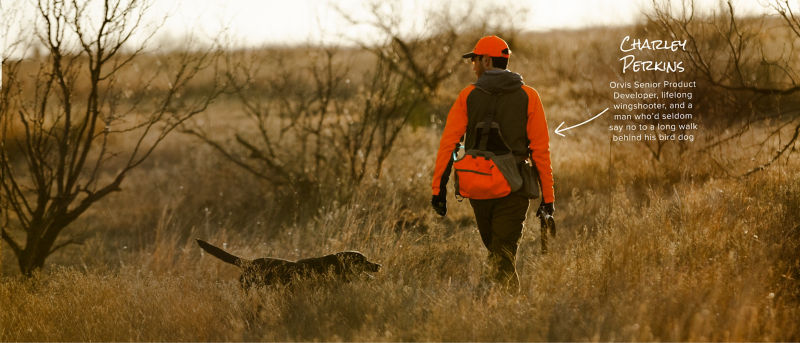 Charley Perkins walking through a field on a hunt with his dog.