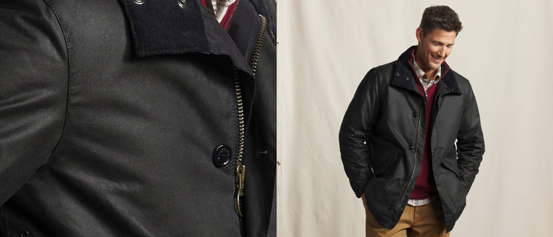 A close-up of a model wearing a Barbour jacket over a flannel shirt and quarter-zip sweater.
