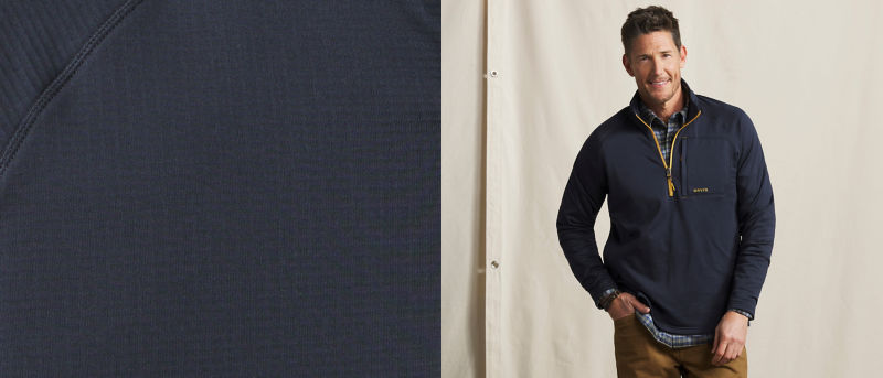 A model wearing a dark blue quarter zip with gold accents over a plaid shirt.