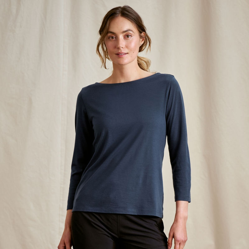 A model stands in front of a canvas drop cloth wearing a navy boatneck tee.