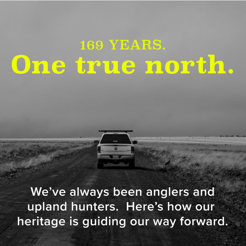 A black and white image of a white truck driving away over a dirt road between two fields with overlaid text saying: One True North | We've always been anglers and upland hunters. Here's how our heritage is guiding our way forward.