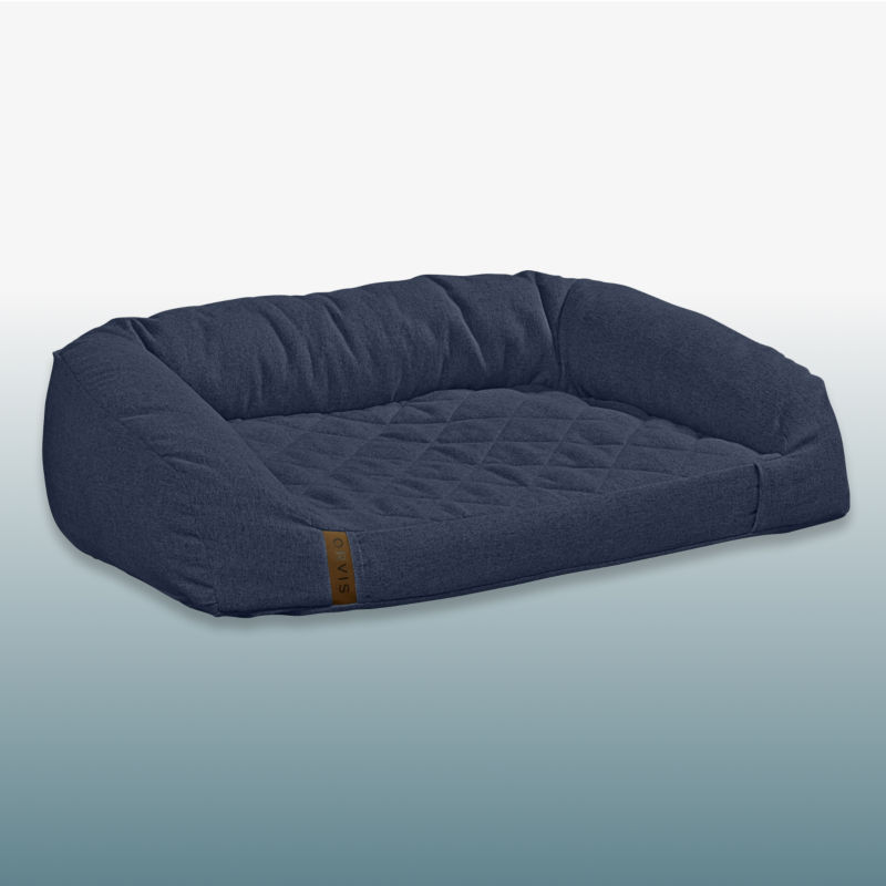 A navy dog bed laid over a blue gradient background.