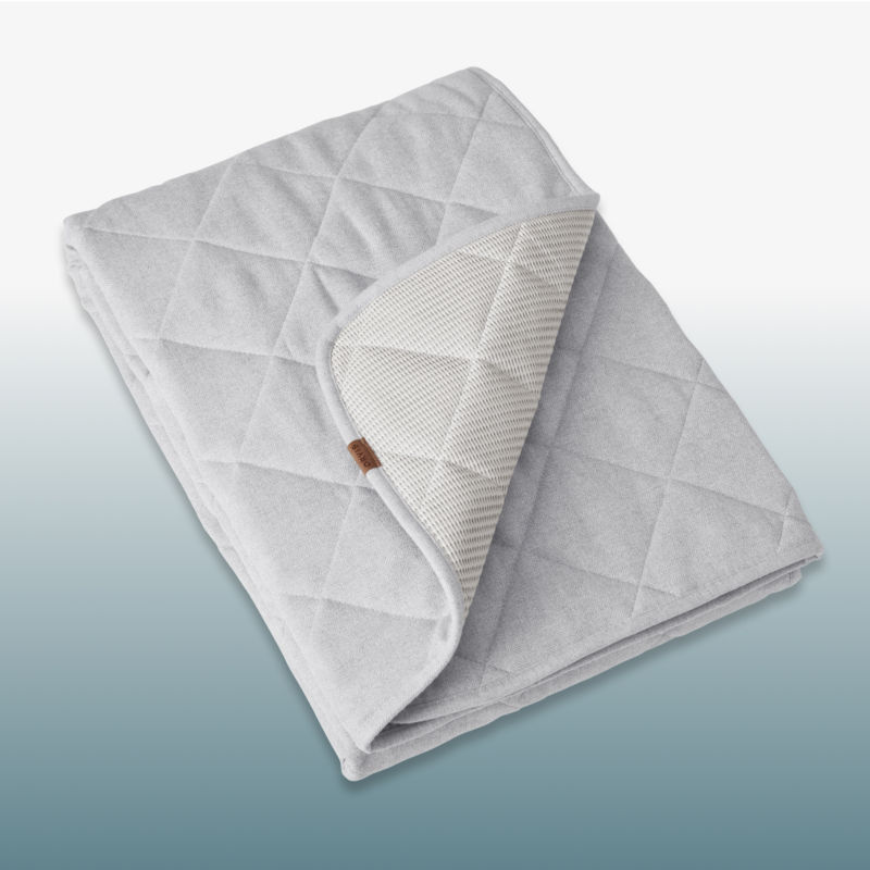 A navy dog bed laid over a blue gradient background.