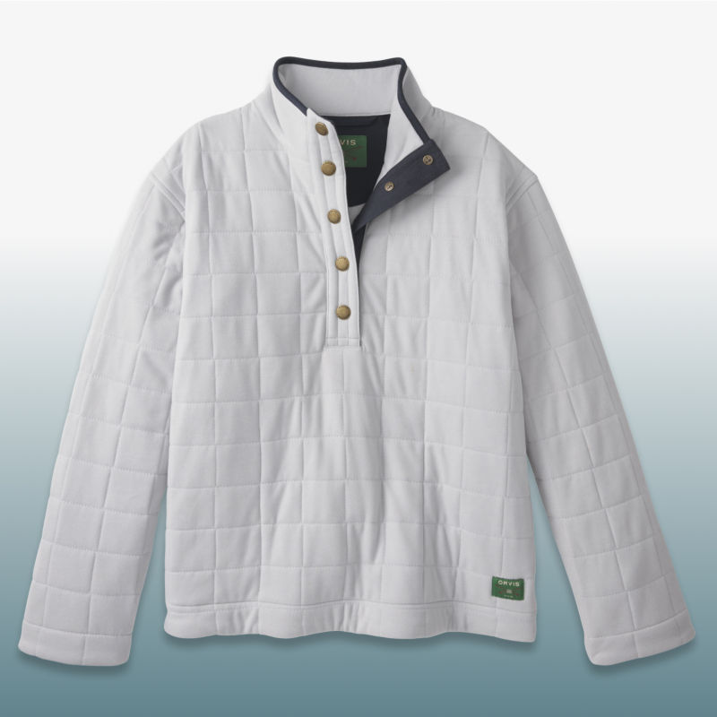 A white quilted sweatshirt with navy trim laid over a blue gradient background.