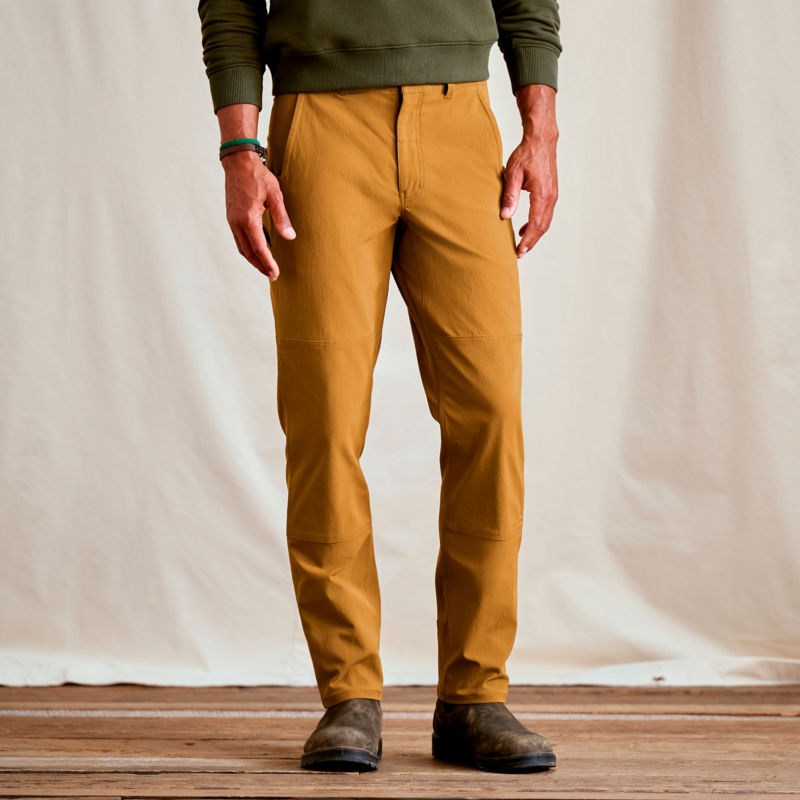 A waist-down view of a model wearing a pair of gold pants.